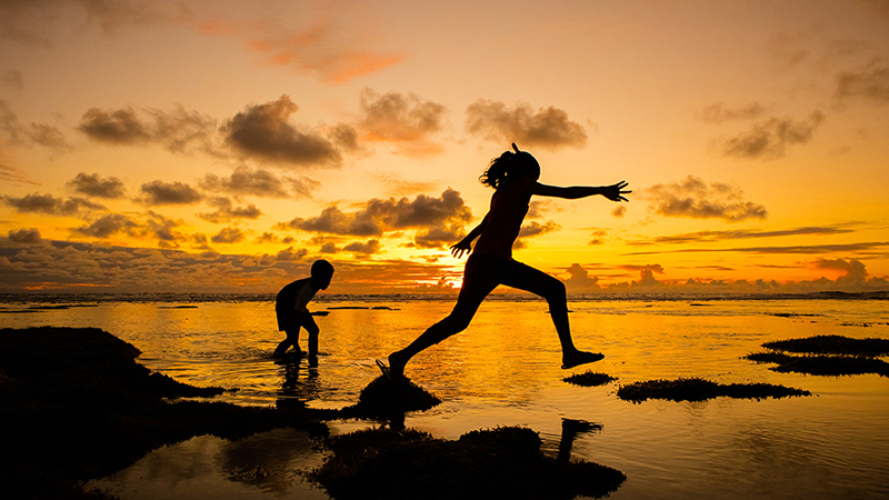 children leaping on the sea shore